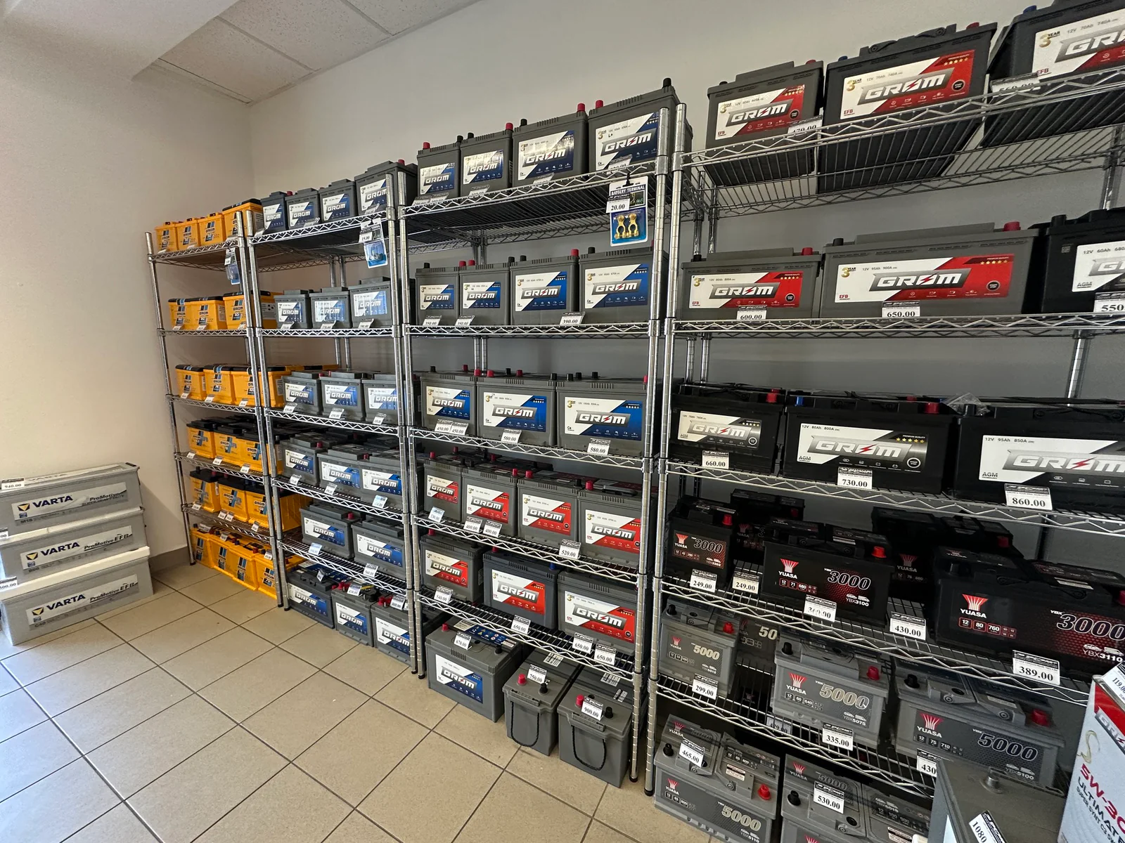 Labelled automotive batteries displayed on continuous runs of Chrome shelving